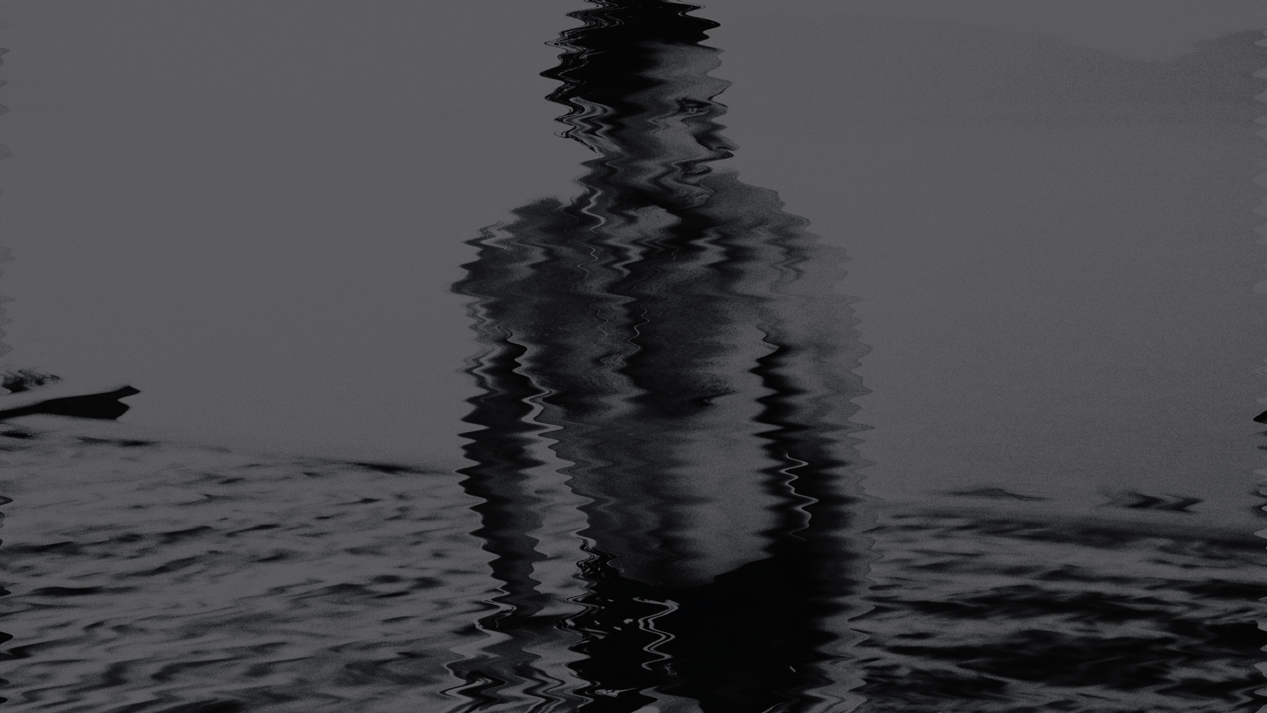 A dark, monochromatic image of a person standing in water, with a noticeable rippled or wavy distortion effect over the entire scene.