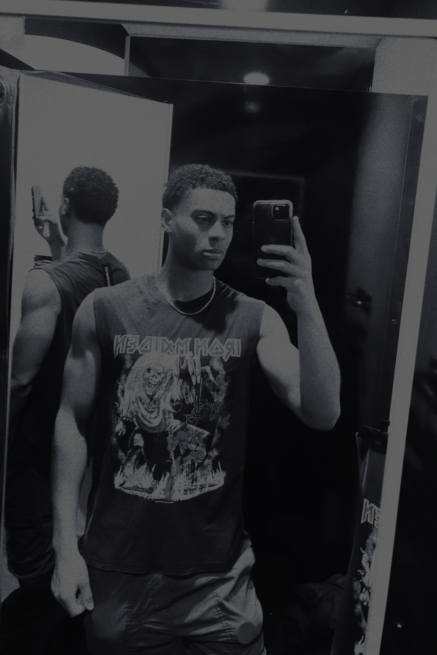 Selfie of a man wearing a graphic t-shirt with text, taking a photo in a mirror, showcasing his casual style.